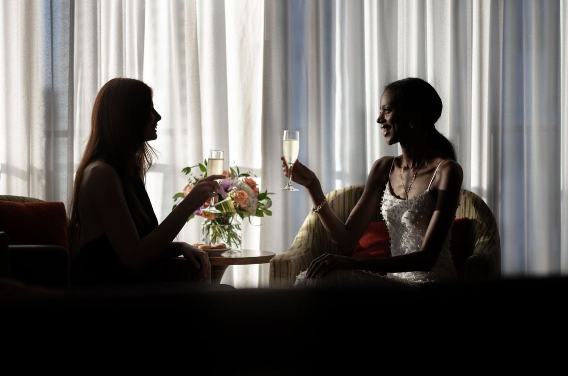 Silhouetted guests raising champagne flutes by a floral vase under soft light at Warwick Seattle