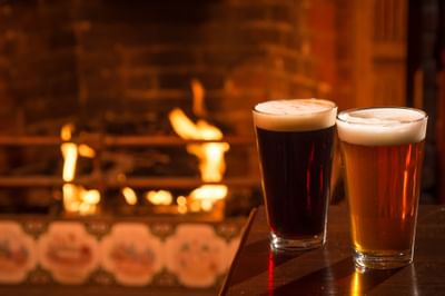 Close-up of 2 beer glasses by a fireplace at Inn at Saratoga