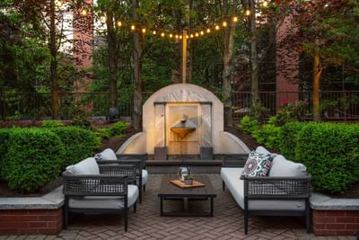 Outdoor patio with seating, lighting, and lush greenery in Harbor Bistro at Portland Harbor Hotel