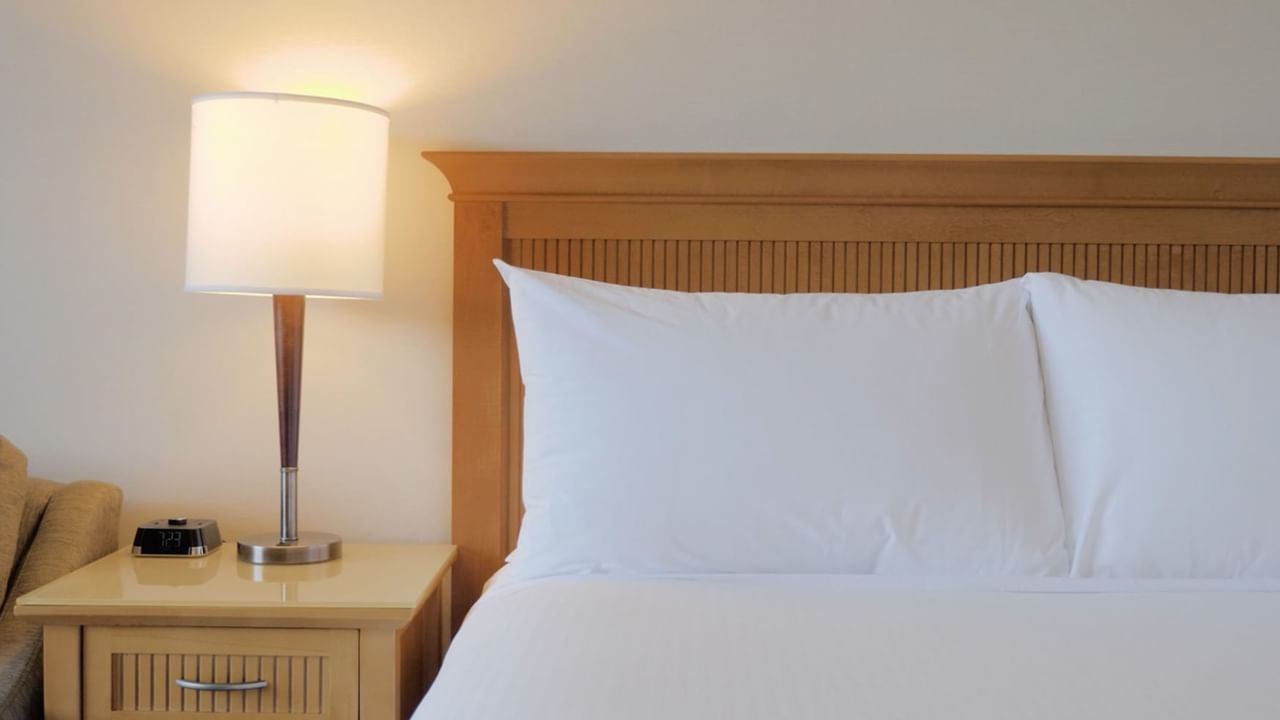 Bed with fitted white sheets, pillows and side lamp