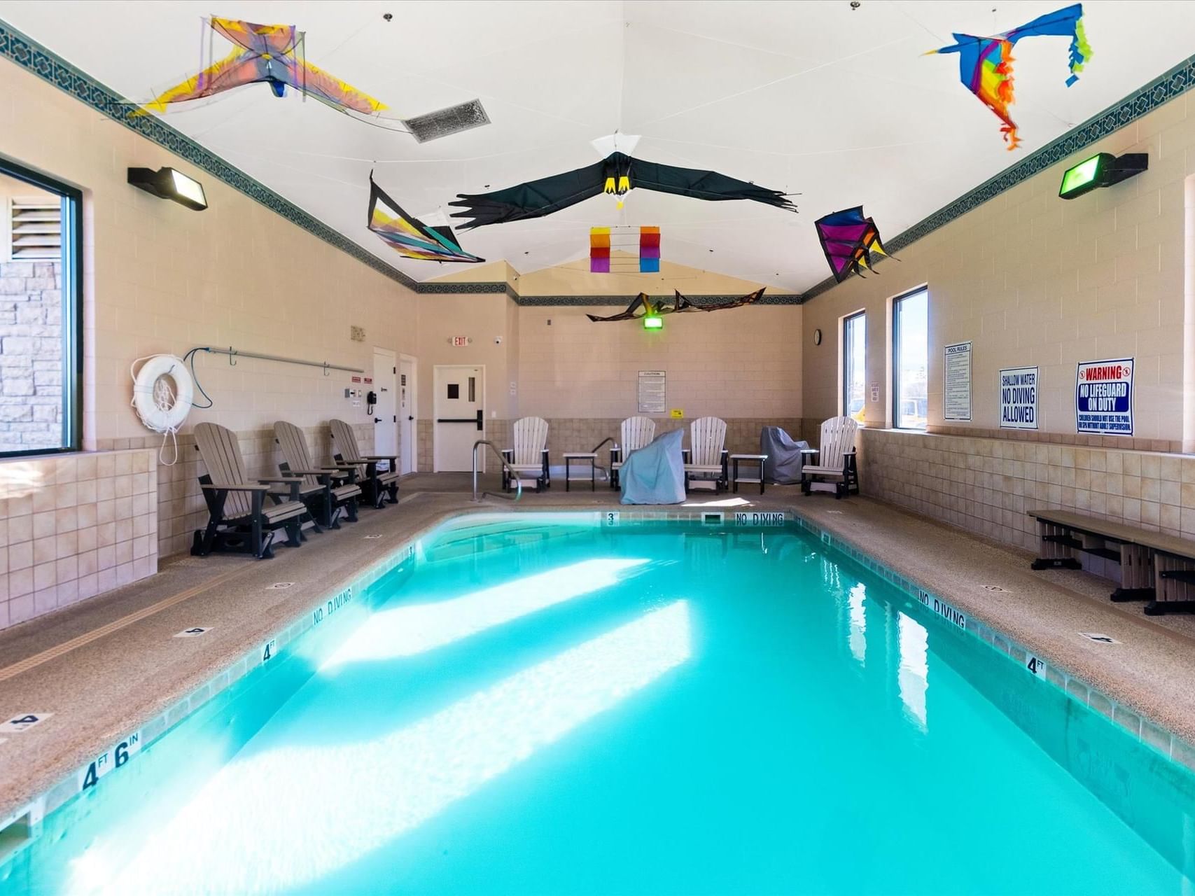Indoor Heated Pool with loungers by windows at Boothill Inn & Suites