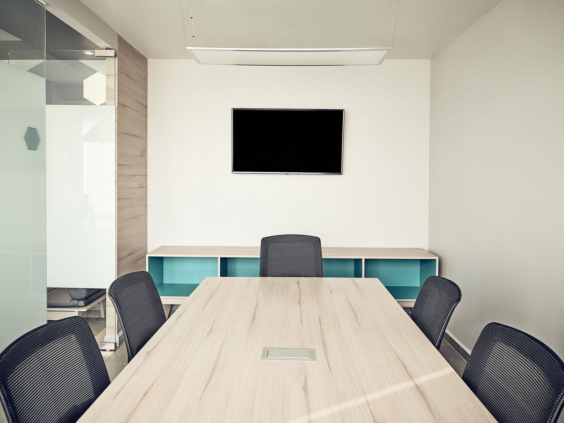 Mesa de conferencias y televisor de pared en una sala de reuniones de One Hotels