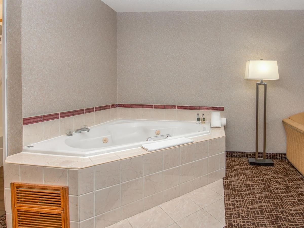 A hotel room with a jetted tub, a couch, a lamp, and a framed picture.