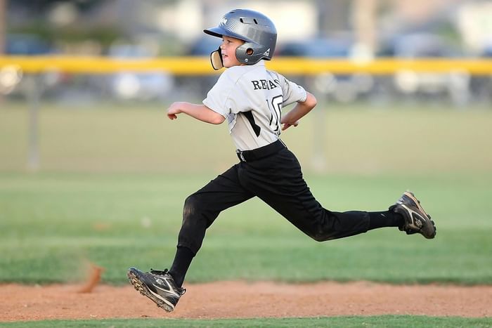 Little boy running in a baseball field near Anaheim Portofino Inn & Suites