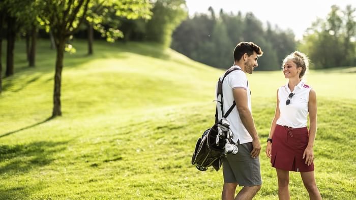 A couple looking at each other on a golf course near Falkensteiner Balance Resort Stegersbach