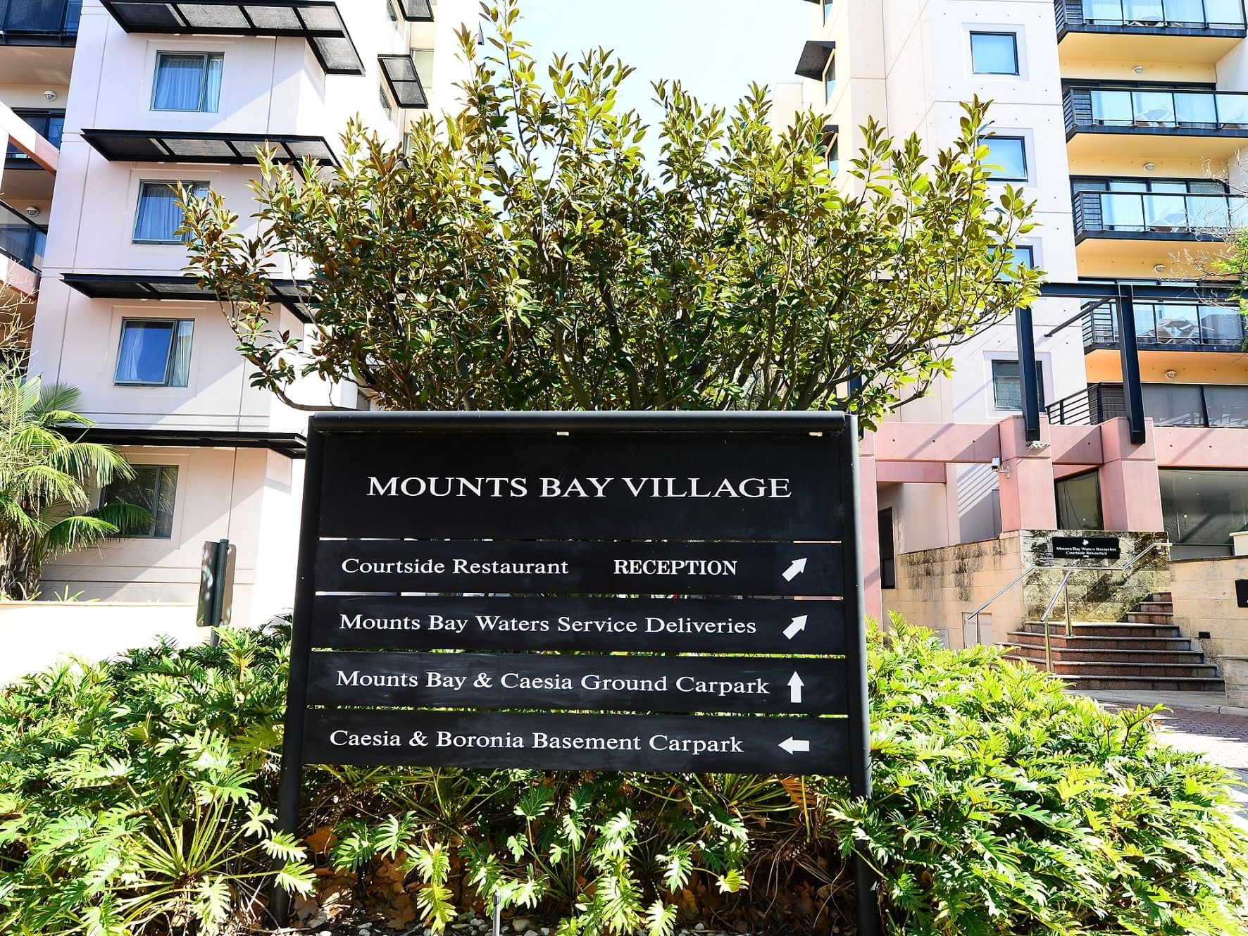 Signboard with directions by a tree at Nesuto Mounts Bay