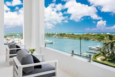 Modern grey armchairs beside a glass railing at Zenza Hotel turks and caicos hotel with water view balconies