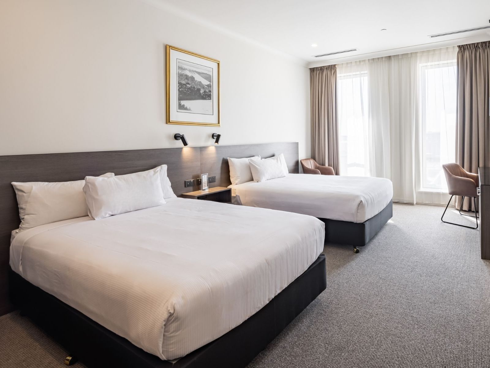 Deluxe Twin room featuring a king-size bed, armchair, and large windows with sheer curtains at Duxton Hotel Perth