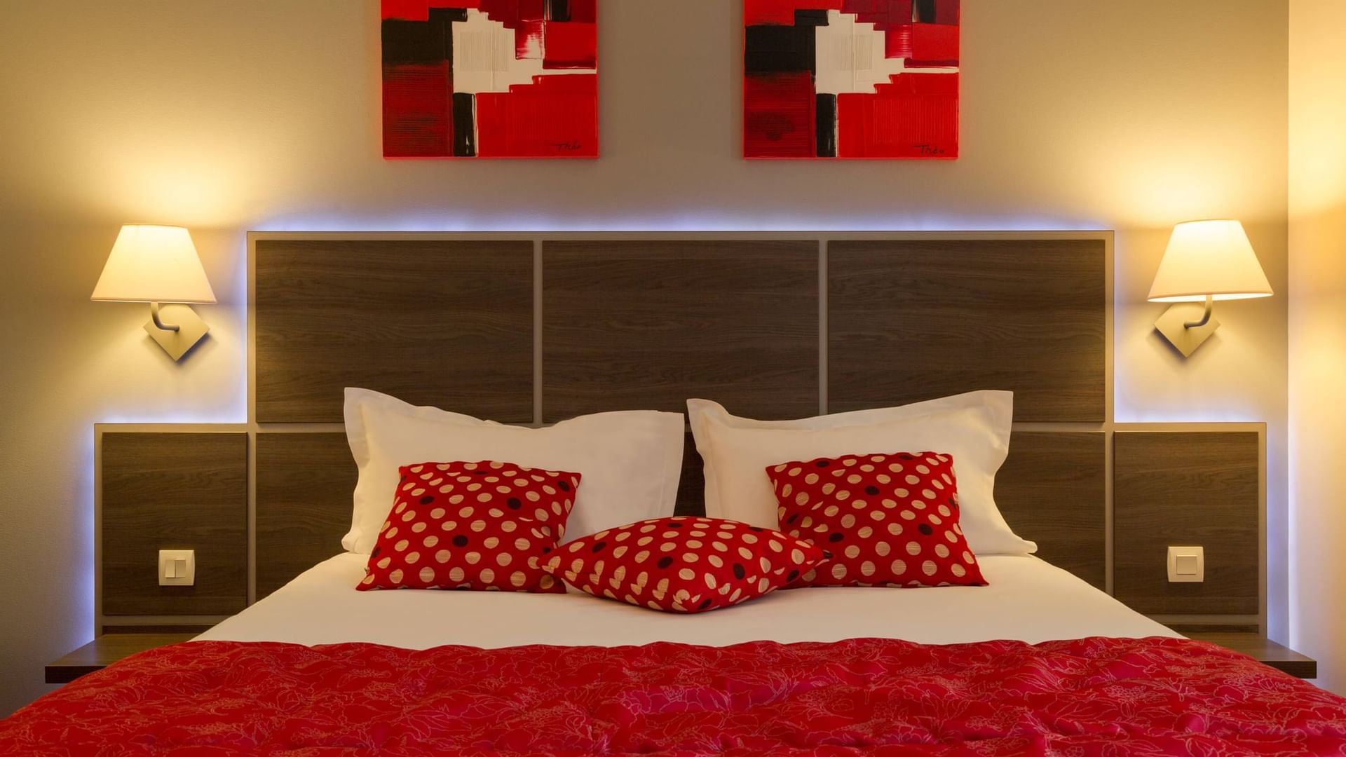 Closeup of a bed with red & white bedding at Originals Hotels