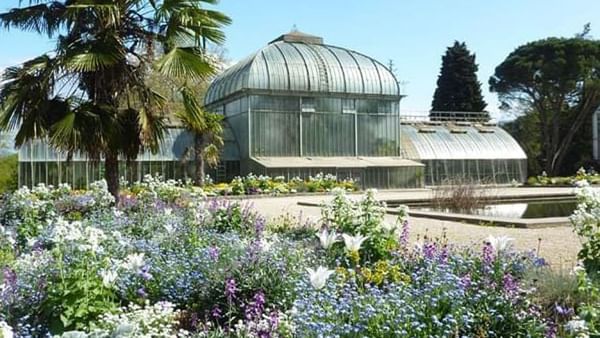 Jardin Botanique with Glass conservatory by a pond surrounding flower beds near Warwick Geneva