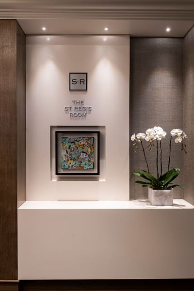 Wall display featuring The St Regis Room sign and potted orchid at The St. Regis Hotel, a boutique hotel Vancouver
