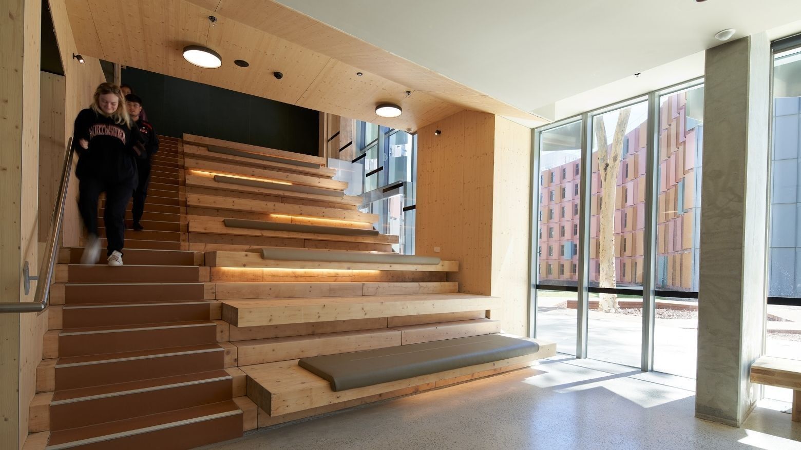 Two people walking up wooden stairs at La Trobe University - North and South Apartments.