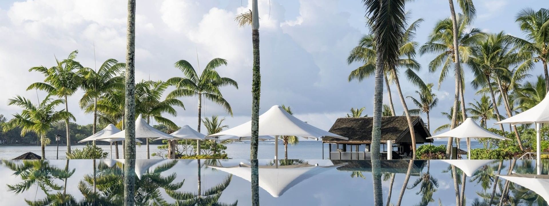 Reflective pool with palm trees and ocean view at Warwick Le Lagon - Vanuatu, Efate