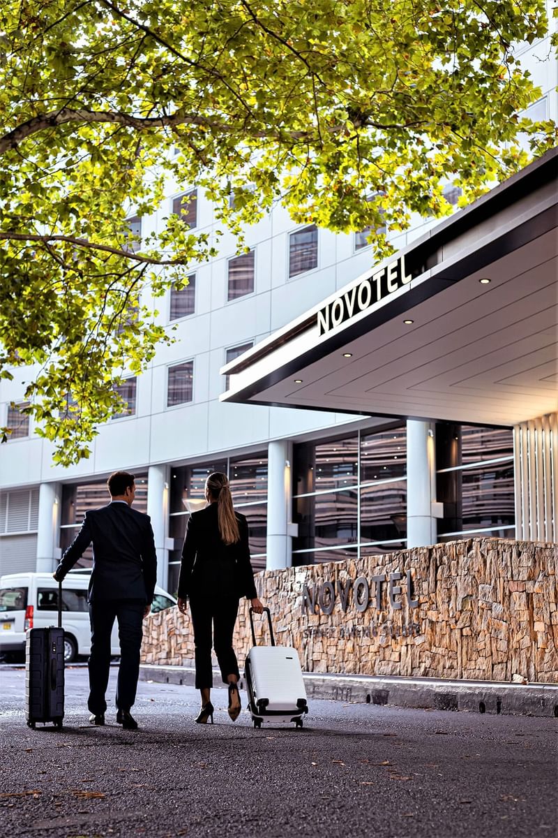 Couple with luggage by the entrance to Novotel Darling Square
