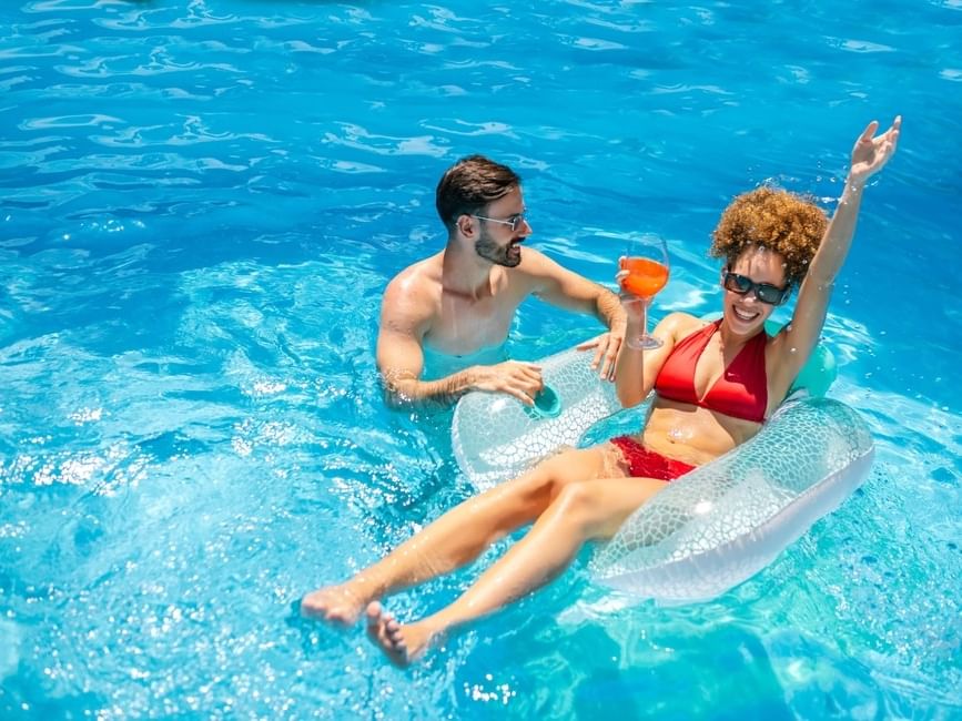 Couple relaxing on pool float with a drink for a romantic getaway.