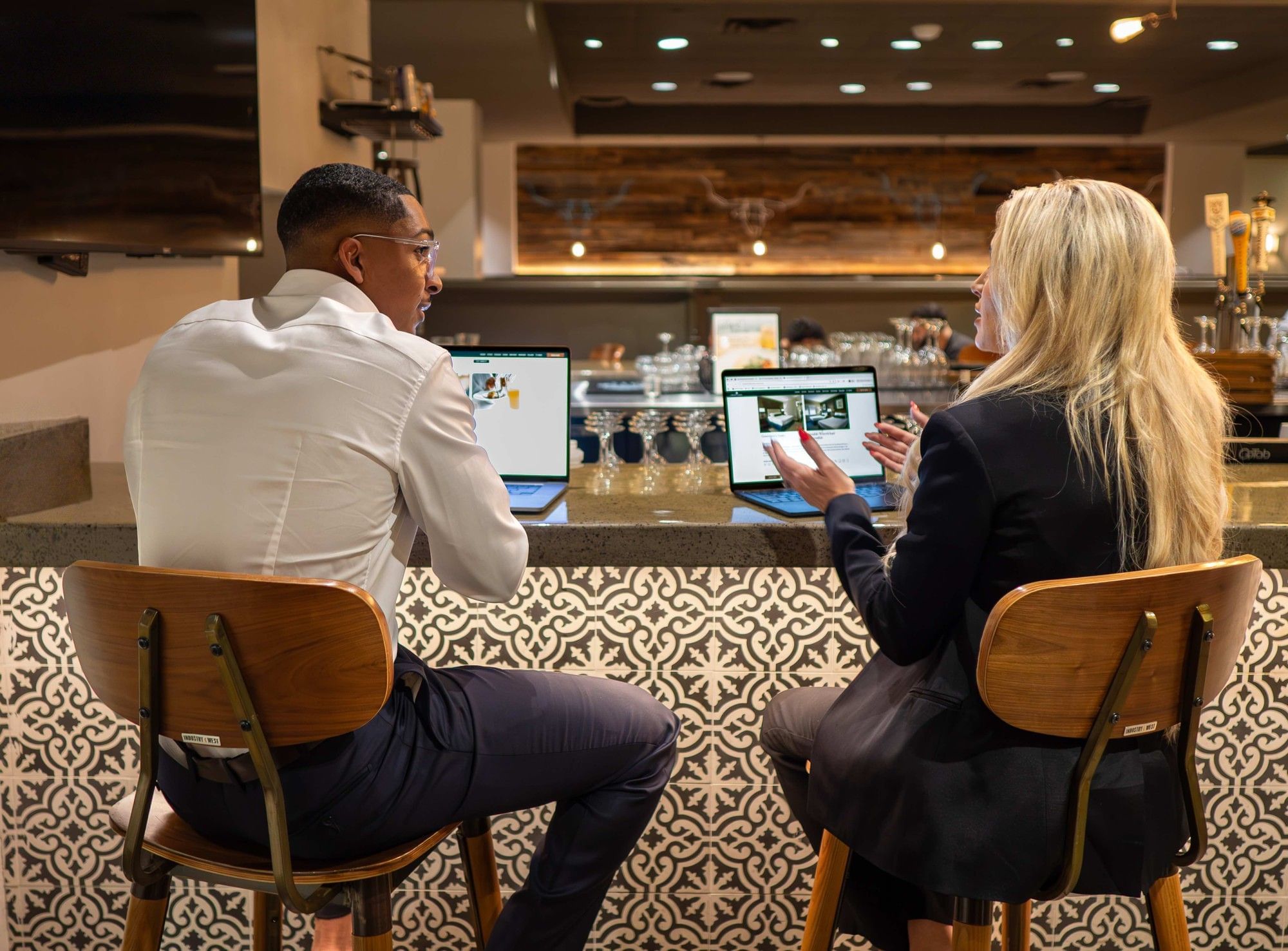 Two people sitting at a bar with laptops