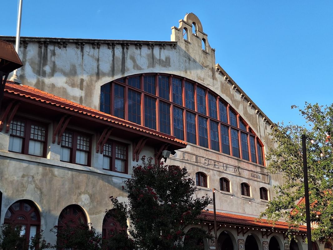 Historic Cowtown Coliseum building by green trees under a clear sky near the plaza near Warwick Melrose Dallas Hotel