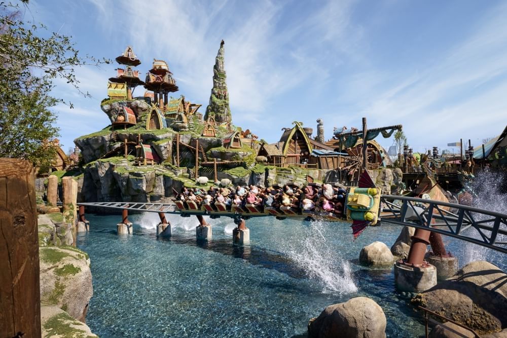 A roller coaster track low to the water gets splashed as rider glide through a Viking Village at Universal's Epic Universe.