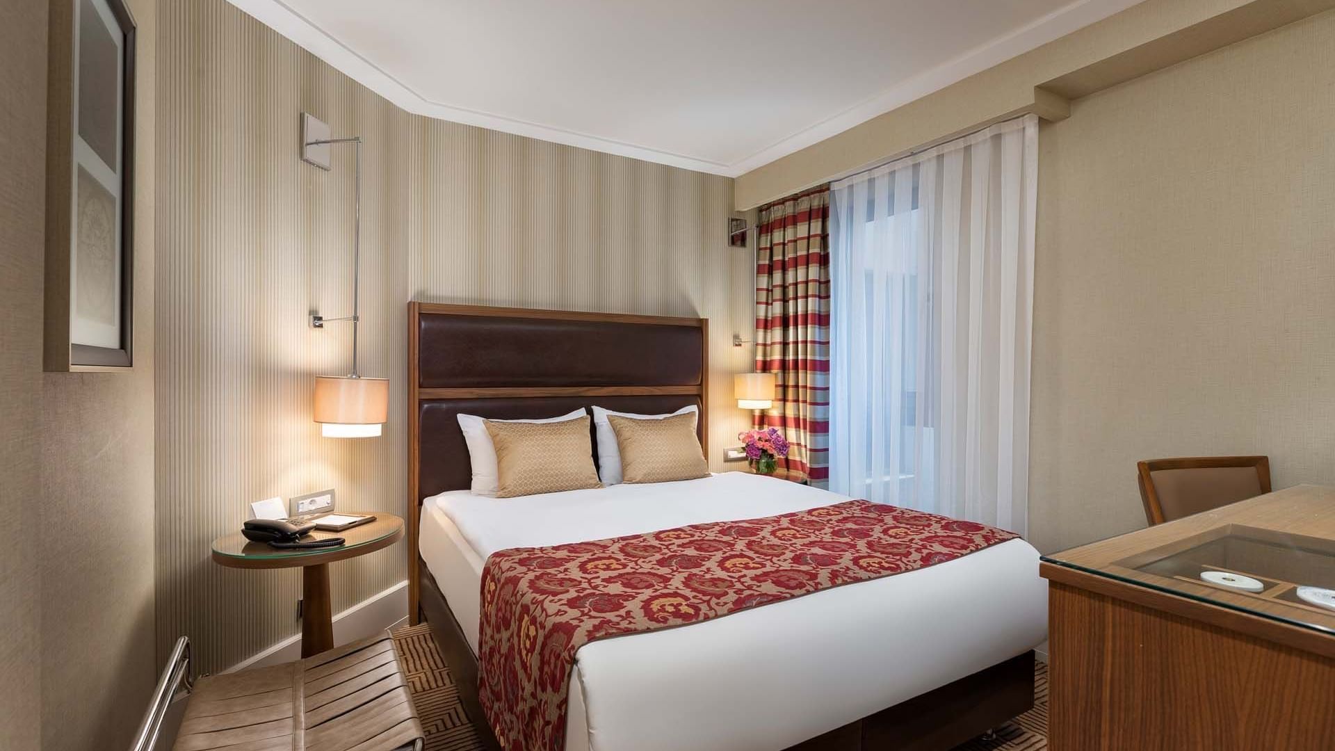 Titanic City Taksim’deki Superior odada, rahat bir yatak ve çalışma masası.