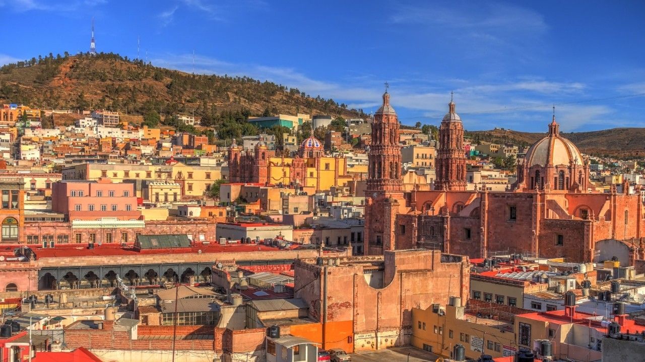 Old cathedrals by colorful houses under a blue sky near the historic Camino Real Pedregal Mexico
