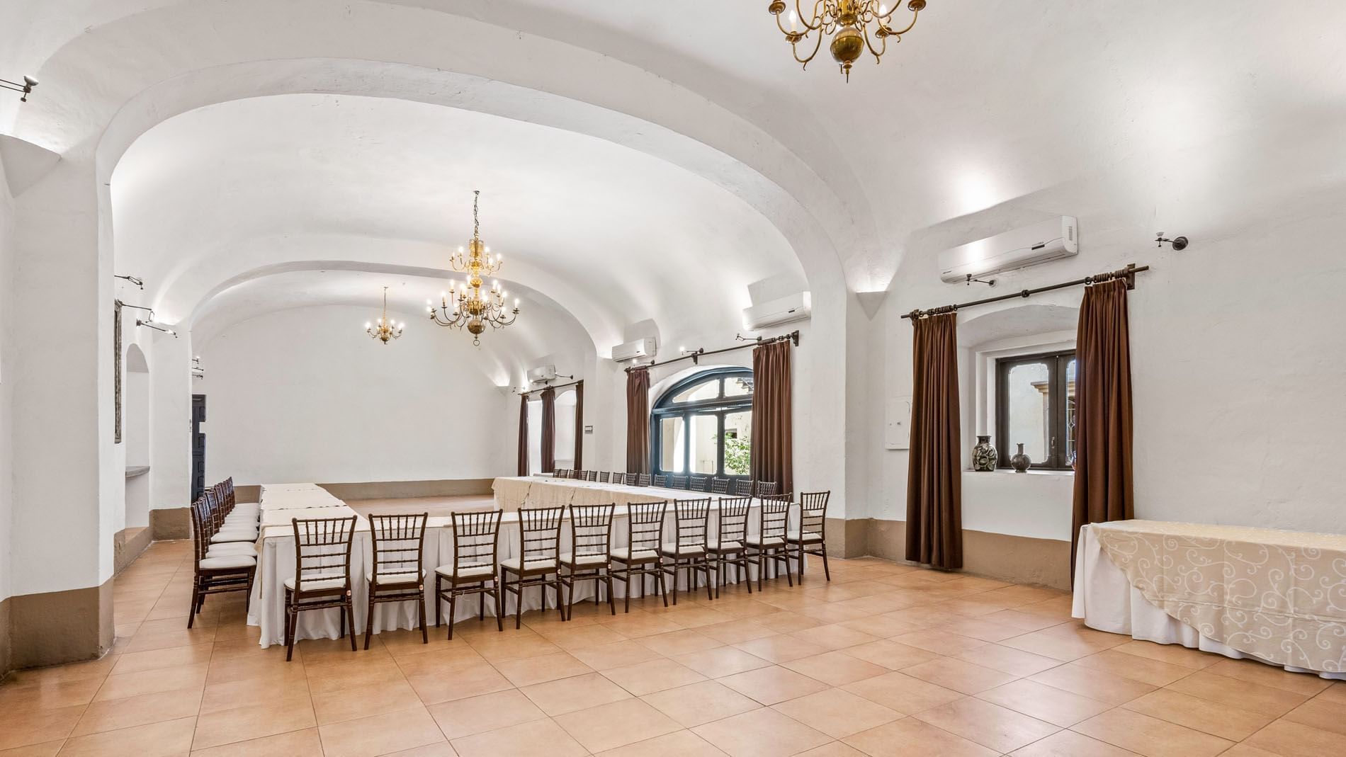 Spacious conference room with white linens, brown curtains, and arched white ceilings in Cholula at Quinta Real Puebla