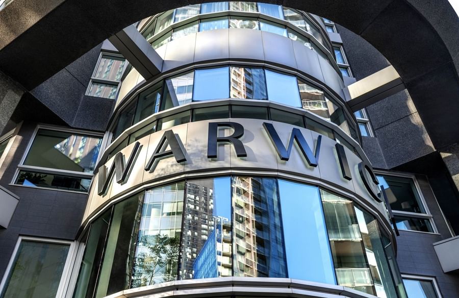 Modern curved glass facade with large silver Warwick signage at Warwick Le Crystal Montreal