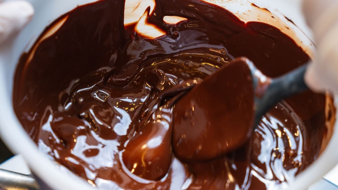 Close-up of a bowl of thick, melted chocolate being stirred at Paramount Hotel Dubai, creating a decadent swirl