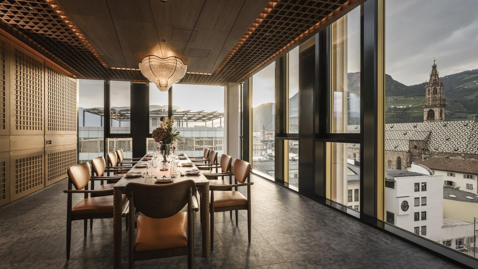 Sala da pranzo con vista sulla città e montagne, tavolo rettangolare e sedie in pelle.
