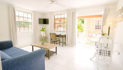 Bright living area with blue sofa beside a wooden coffee table and a small dining set at Worthing Court Apartment