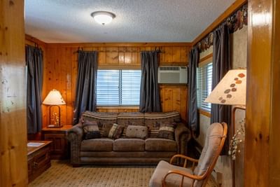 Living area with wood paneling, a comfortable sofa, and inviting lamps in Aspen Cabins at The Ranch at UCross