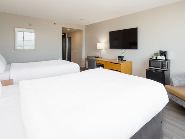 Two beds, desk, TV, chair, and appliances in our modern hotel room.