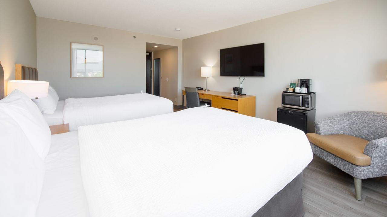 Two beds, desk, TV, chair, and appliances in our modern hotel room.