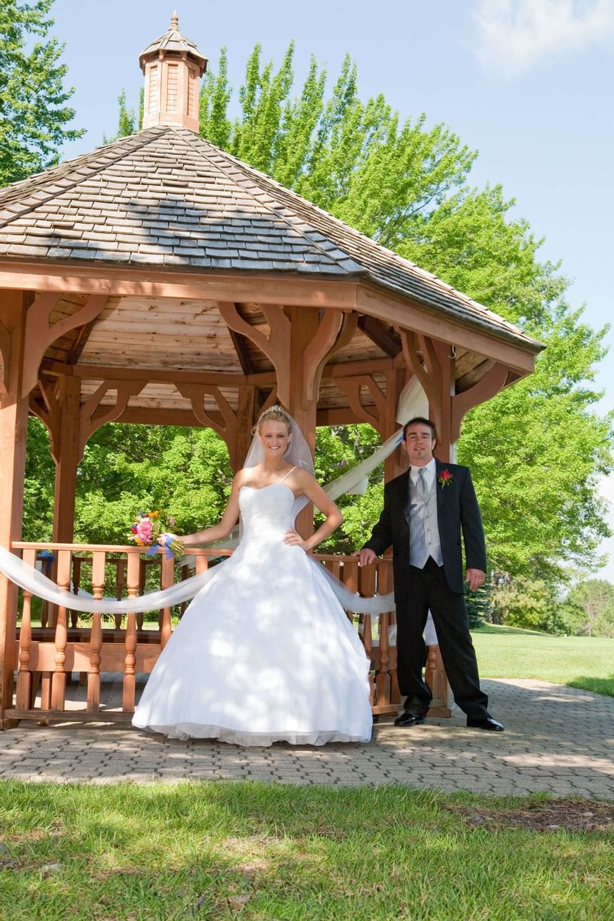Wedding couple posing by a gazebo at Evergreen Resort