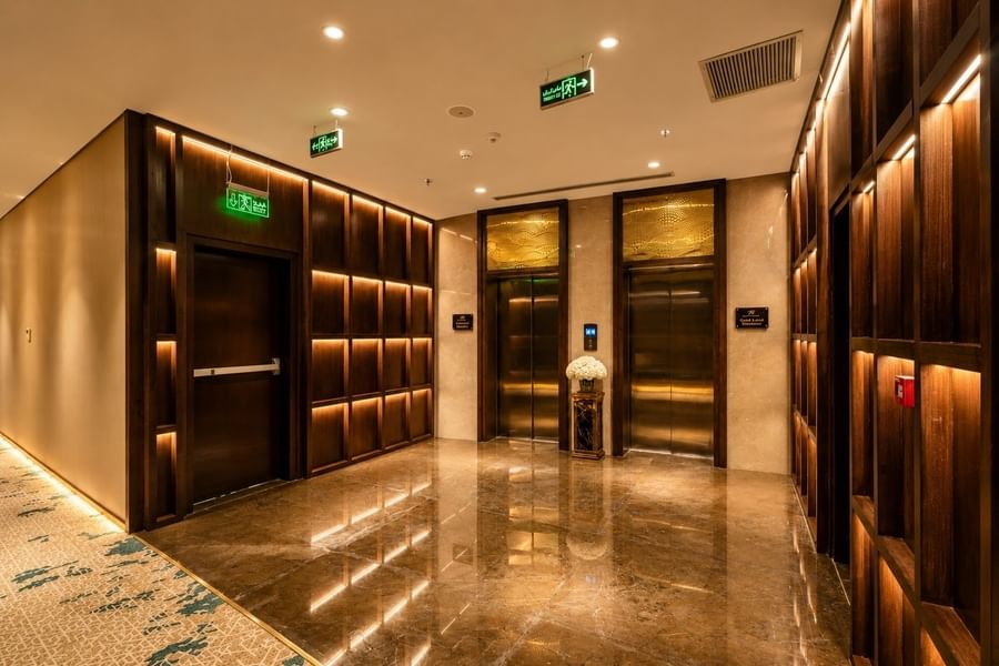 Elevator lobby with back lit wooden wall panels over polished marble floor facing both lifts at Naviti by Warwick Jeddah