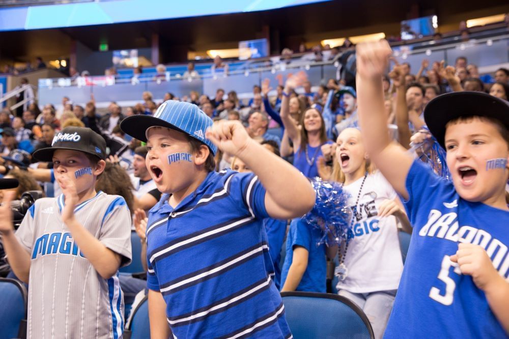 Kids in the crowd wearing Orlando Magic gear cheer enthusiastically.