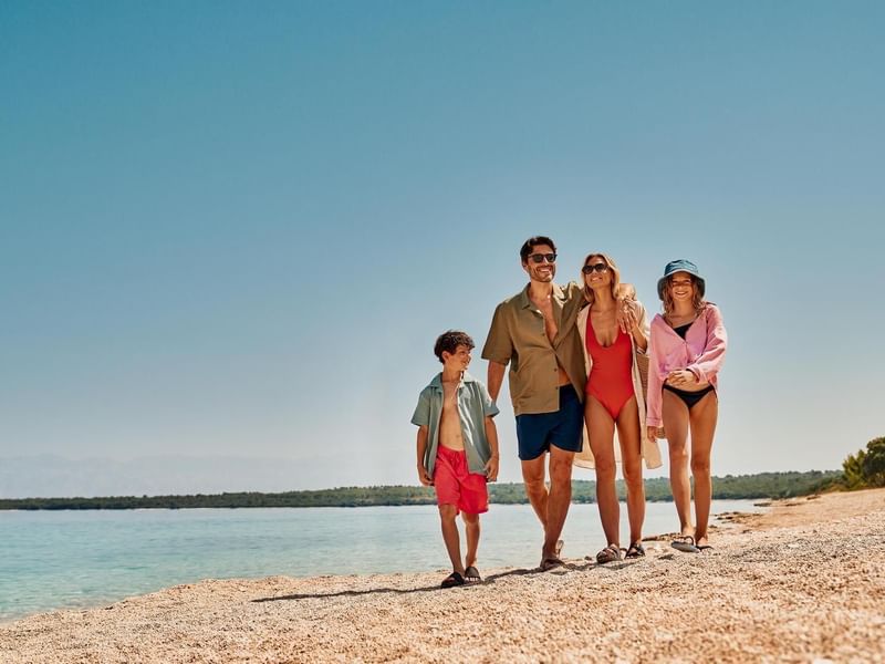 Eine Familie mit vier Personen, bestehend aus zwei Erwachsenen und zwei Kindern, steht am Strand.