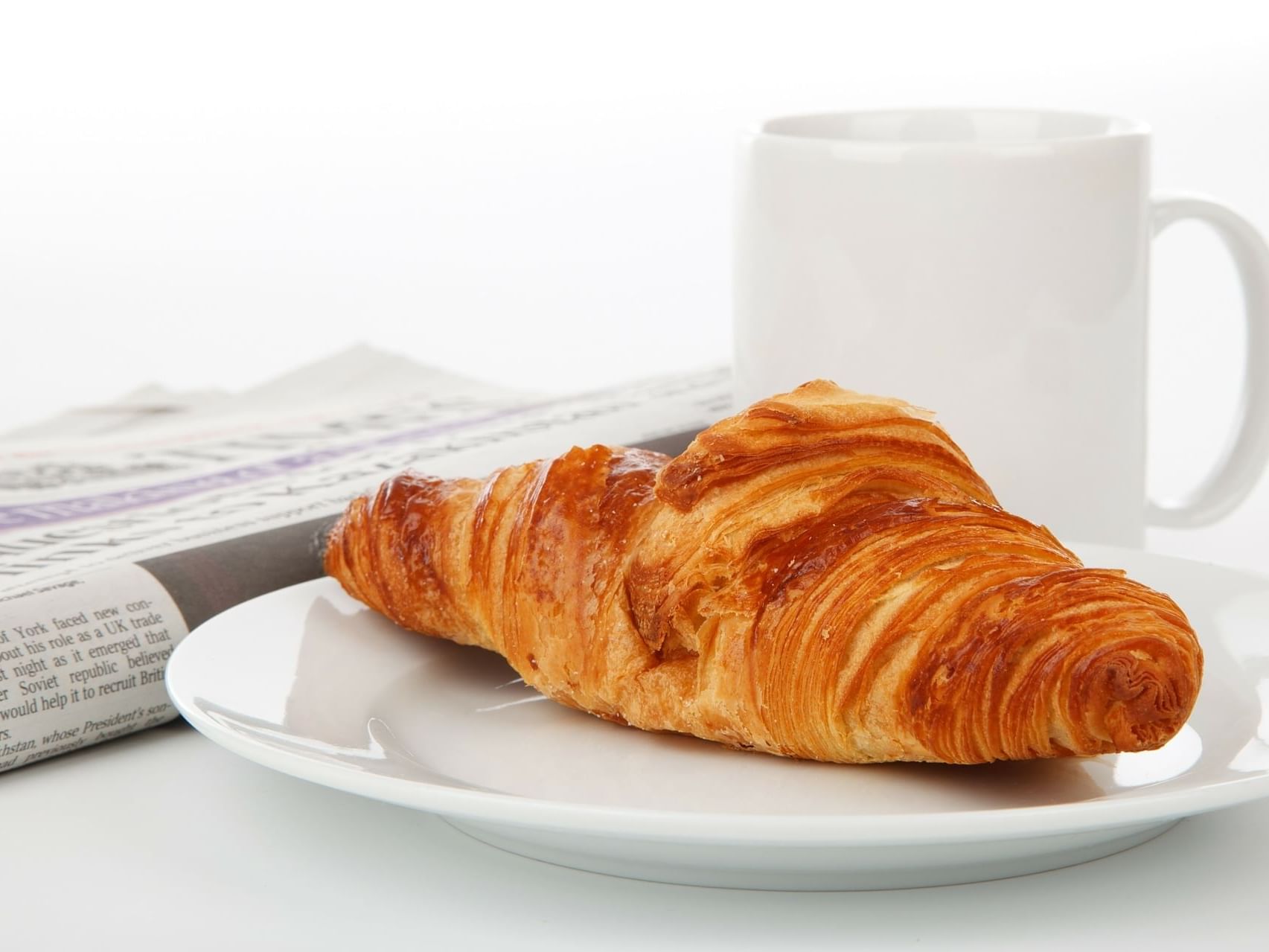 Closeup of a croissant beside a cup of coffee at DOT Hotels