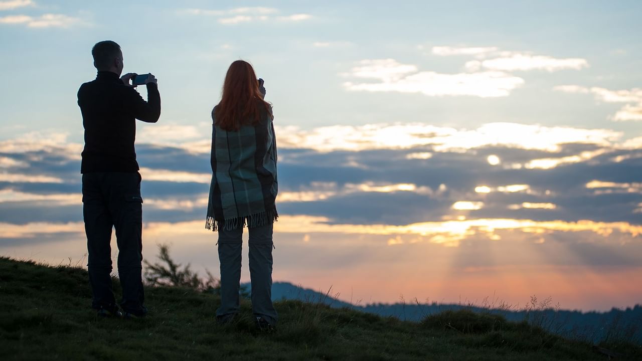 A couple watching the sunrise from a hill
