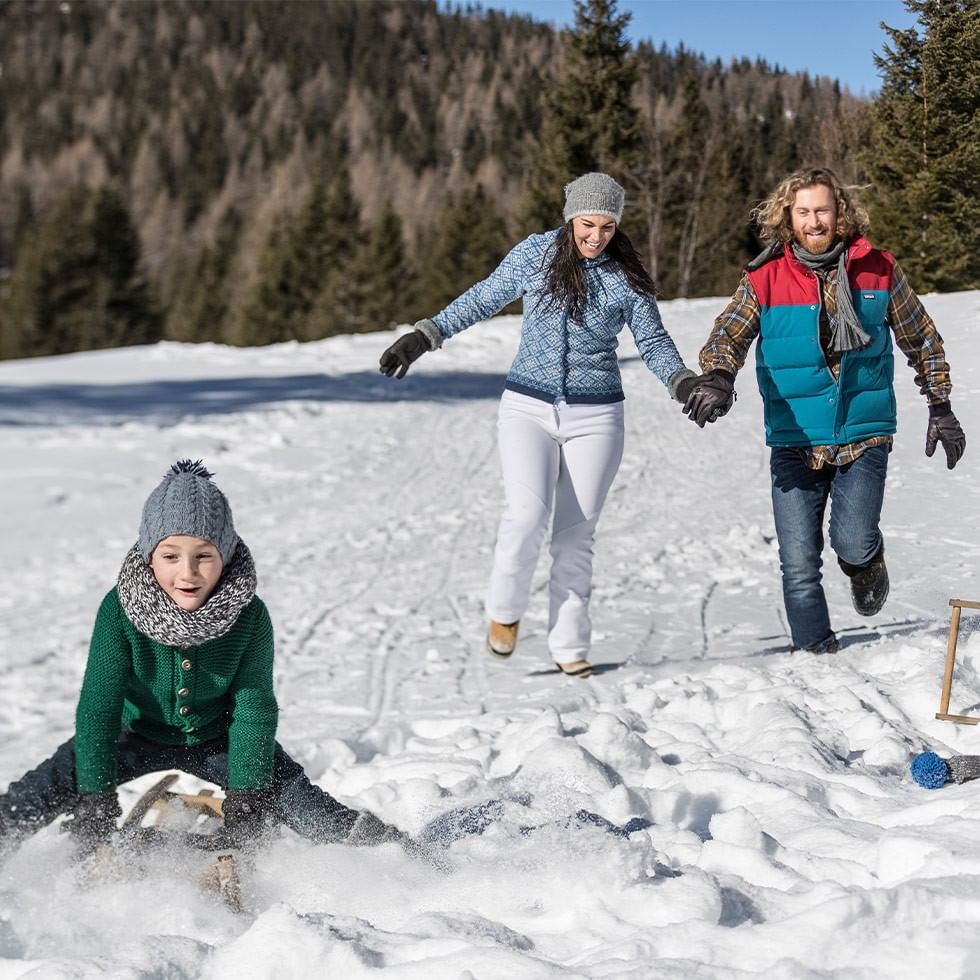 Familie genießt den Schnee mit Schlitten und Ostereier-Schatzsuche.