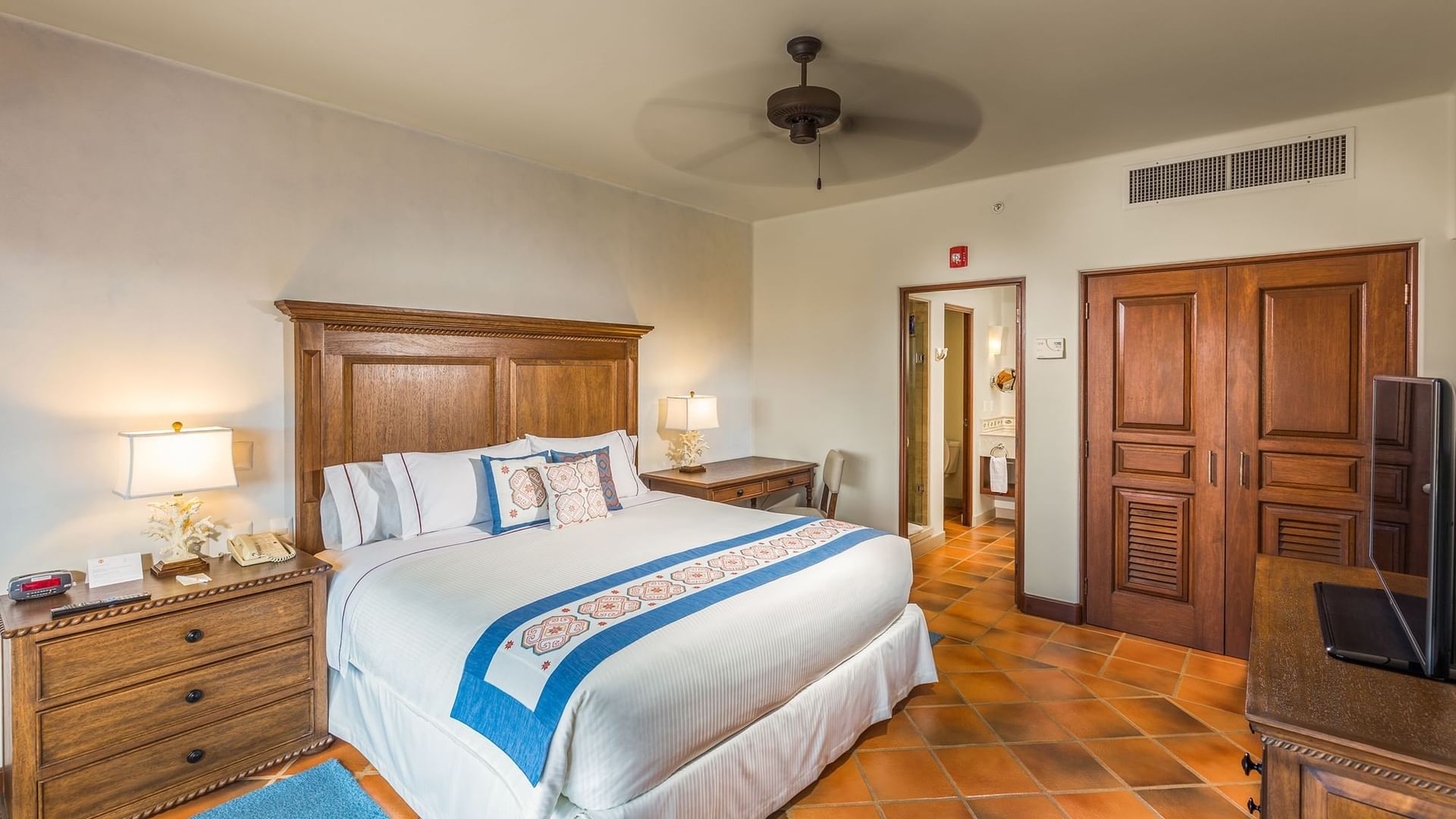 Bedroom with king bed wooden furniture and en suite bathroom inside the Three Bedroom Villa at Hacienda Del Mar Los Cabos.