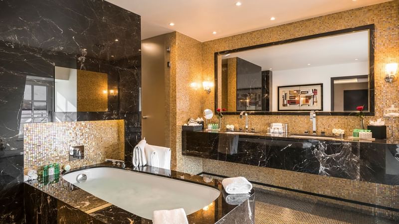 Bathroom vanity area with bathtub in Grand Place Suite at Warwick Brussels