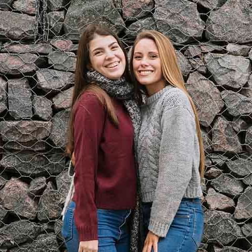 two girls wearing sweaters pose for a picture