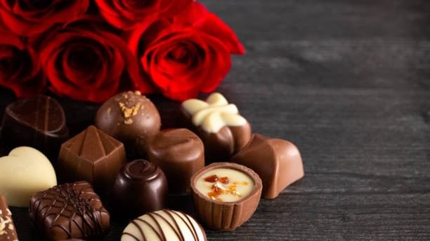 Red roses and assorted chocolates on dark background showcasing Romance Package.