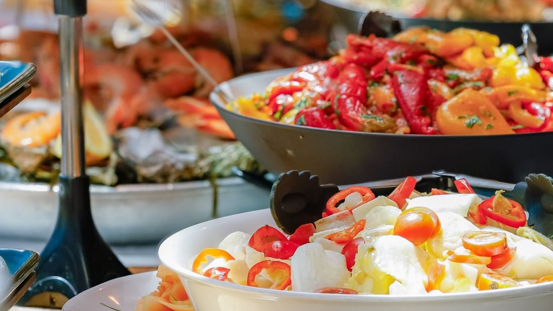 Buffet table with various food dishes, including seafood, salads, and vegetables, arranged in bowls and trays.