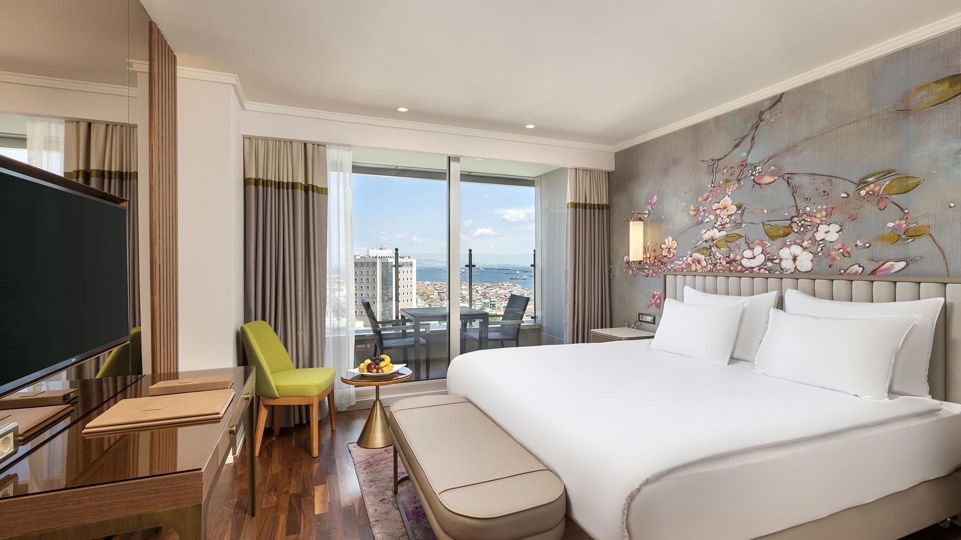 Titanic Port Bakırköy'de, Büyük bir yatağa, balkona ve cam kapılardan şehir manzarasına sahip lüks Executive oda.