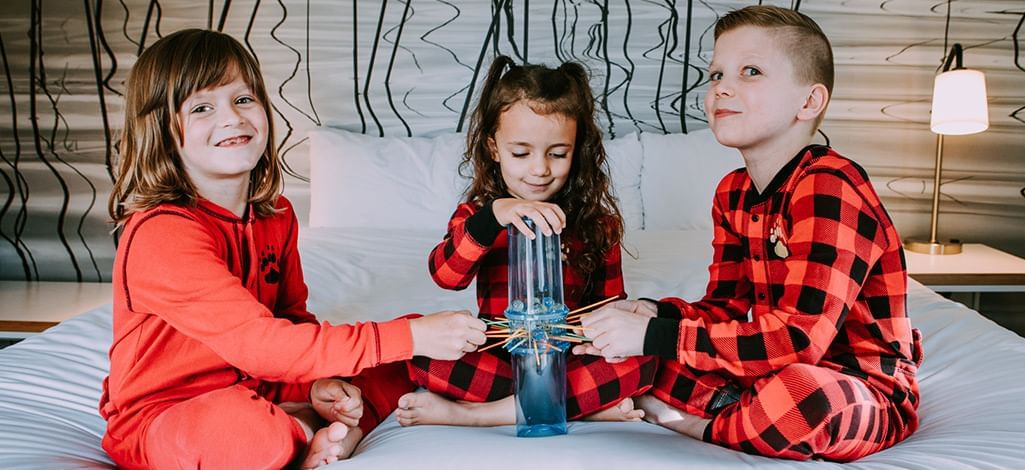 Three kids sit on the bed