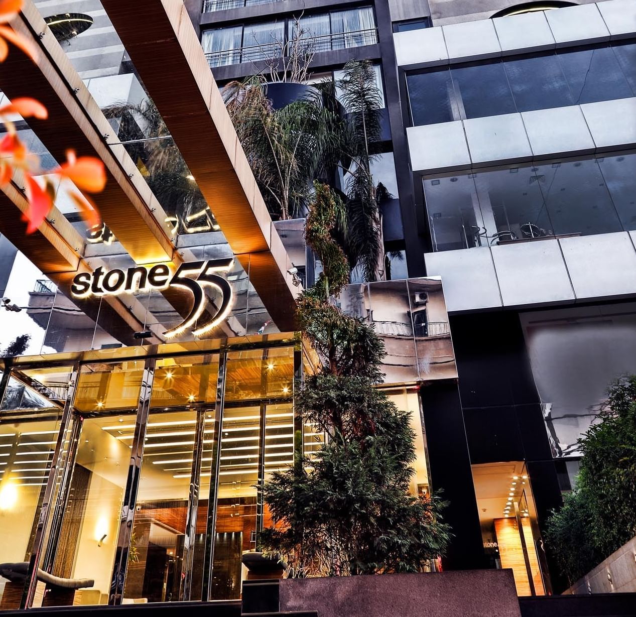 Exterior view of the Warwick Stone 55 Hotel Beirut with a glass entrance under a modern high-rise facade near palm trees