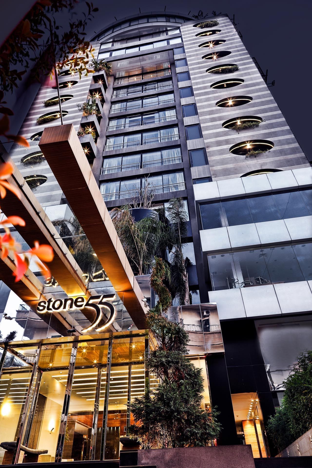 Exterior view of the Warwick Stone 55 Hotel Beirut with a glass entrance under a modern high-rise facade near palm trees