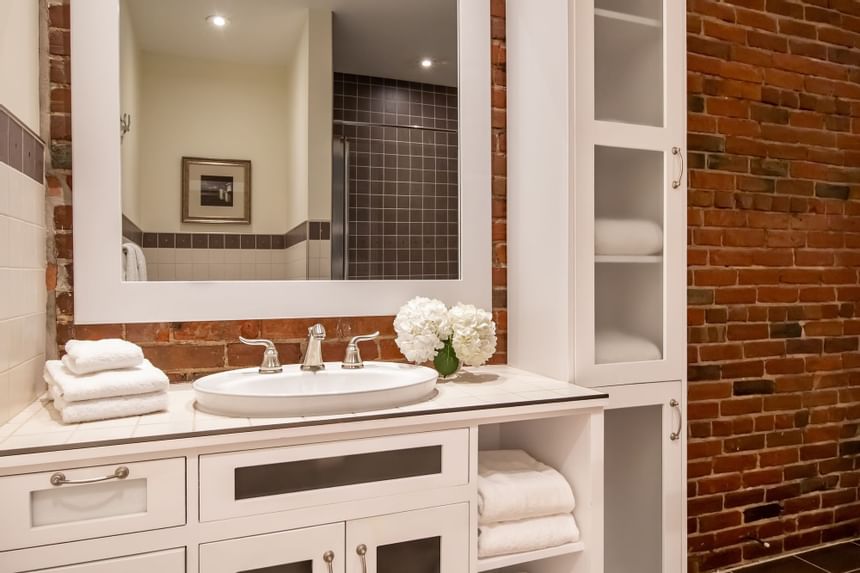 Bathroom vanity with fresh flowers & towels in Premiere Loft Town & Country at Retro Suites Hotel