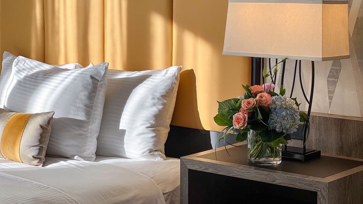 Accessible Executive Room with flowers by a bed under a yellow tufted headboard at Warwick Seattle